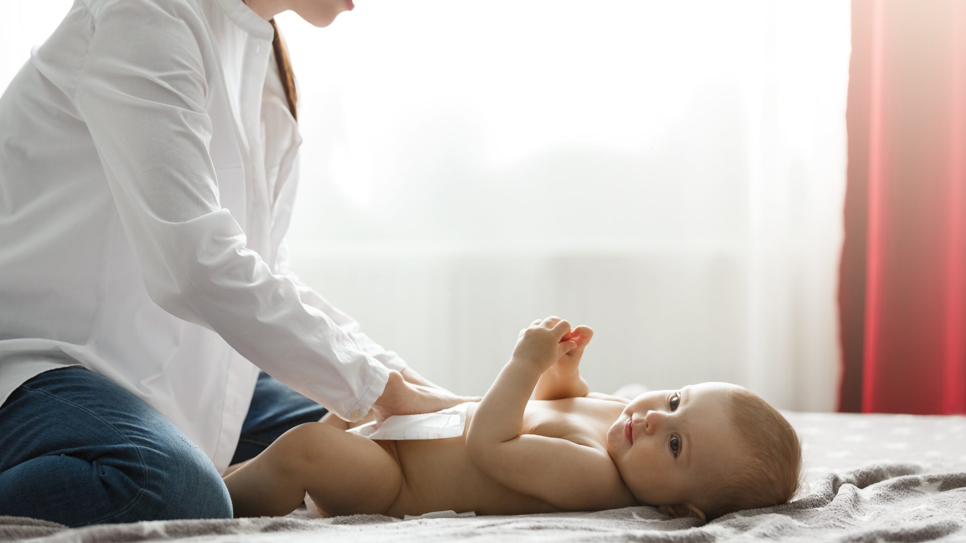 Seorang bayi berbaring dan sedang dipijat ibunya